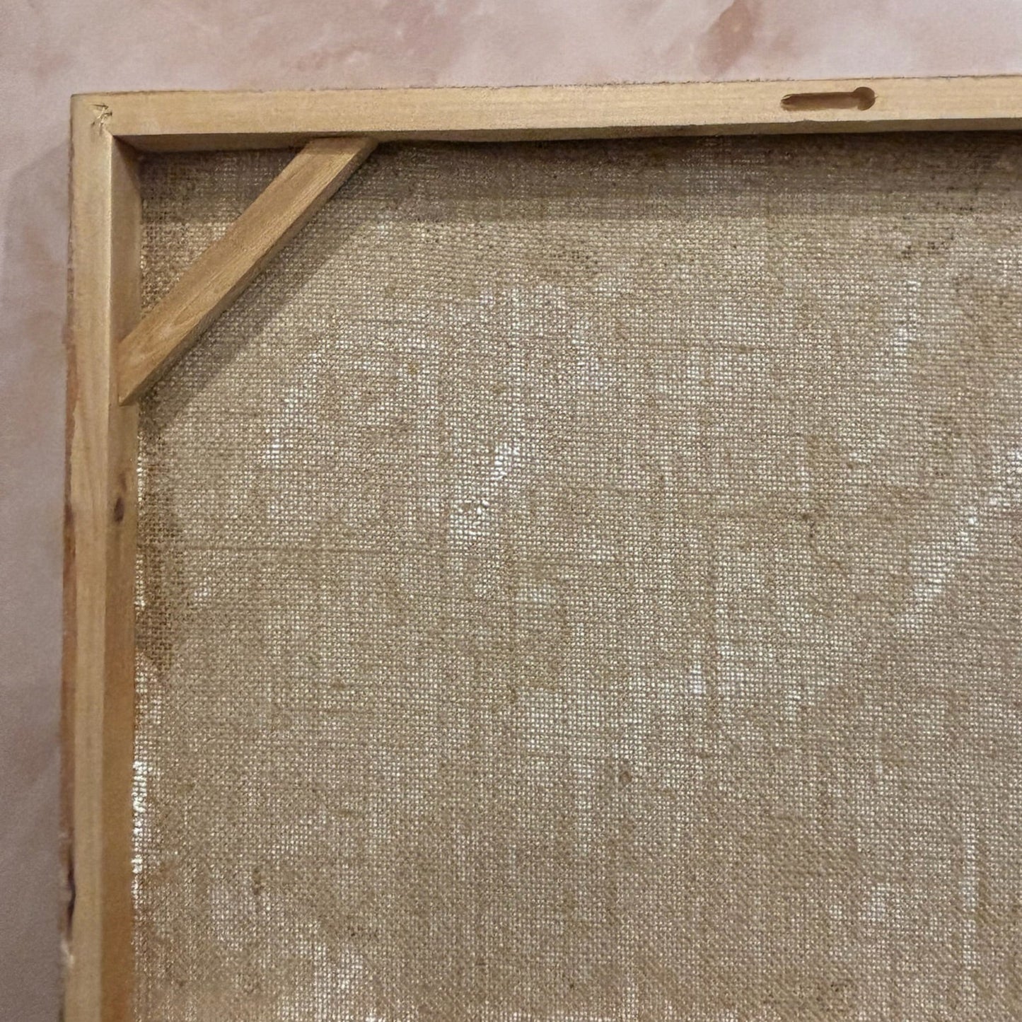 Wooden picture frame with a textured beige mat against a pinkish-brown wall.