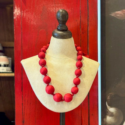 Red necklace on a mannequin against a red background