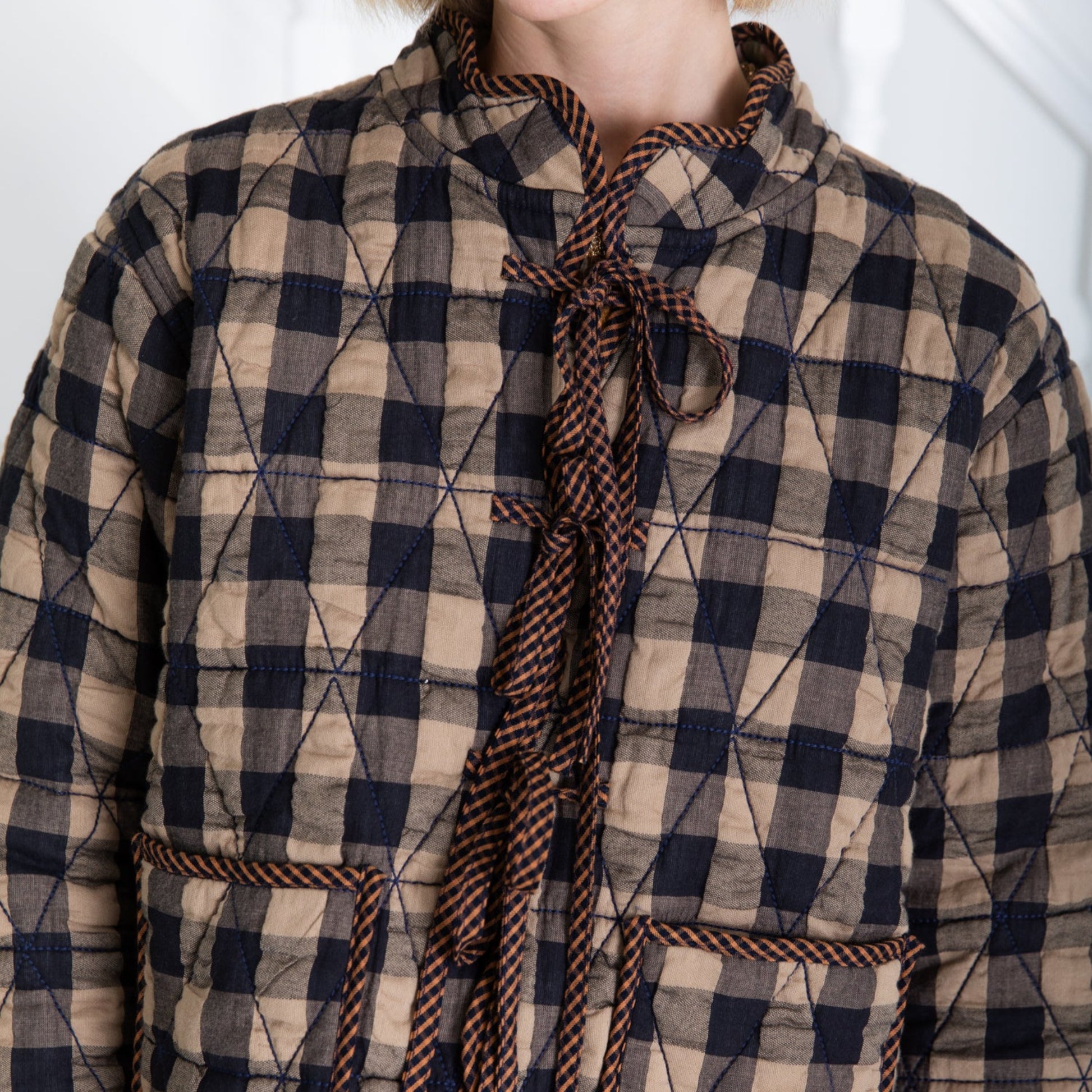 Quilted checkered coat with a tie detail on a white background
