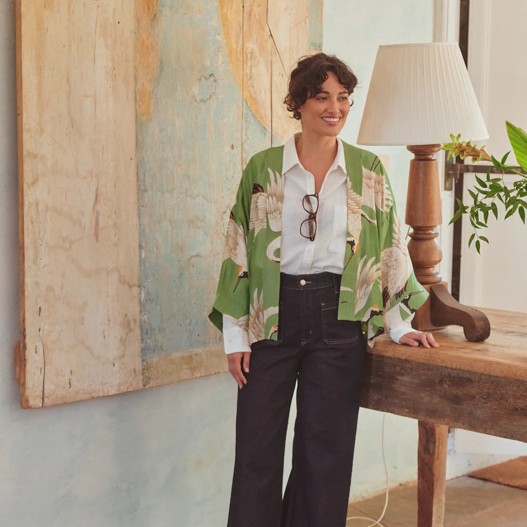 Woman in a floral shirt and black pants standing in a room with a large map on the wall.