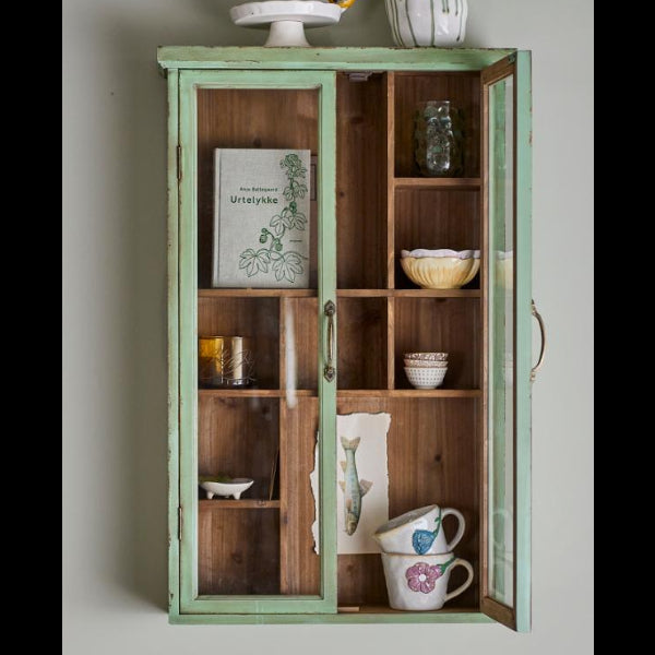 Wooden cabinet with open doors displaying various items on a light gray background