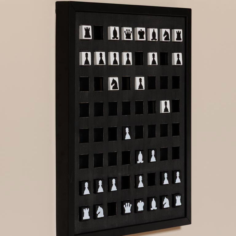 Black frame with cut-out shapes of chess pieces on a beige background